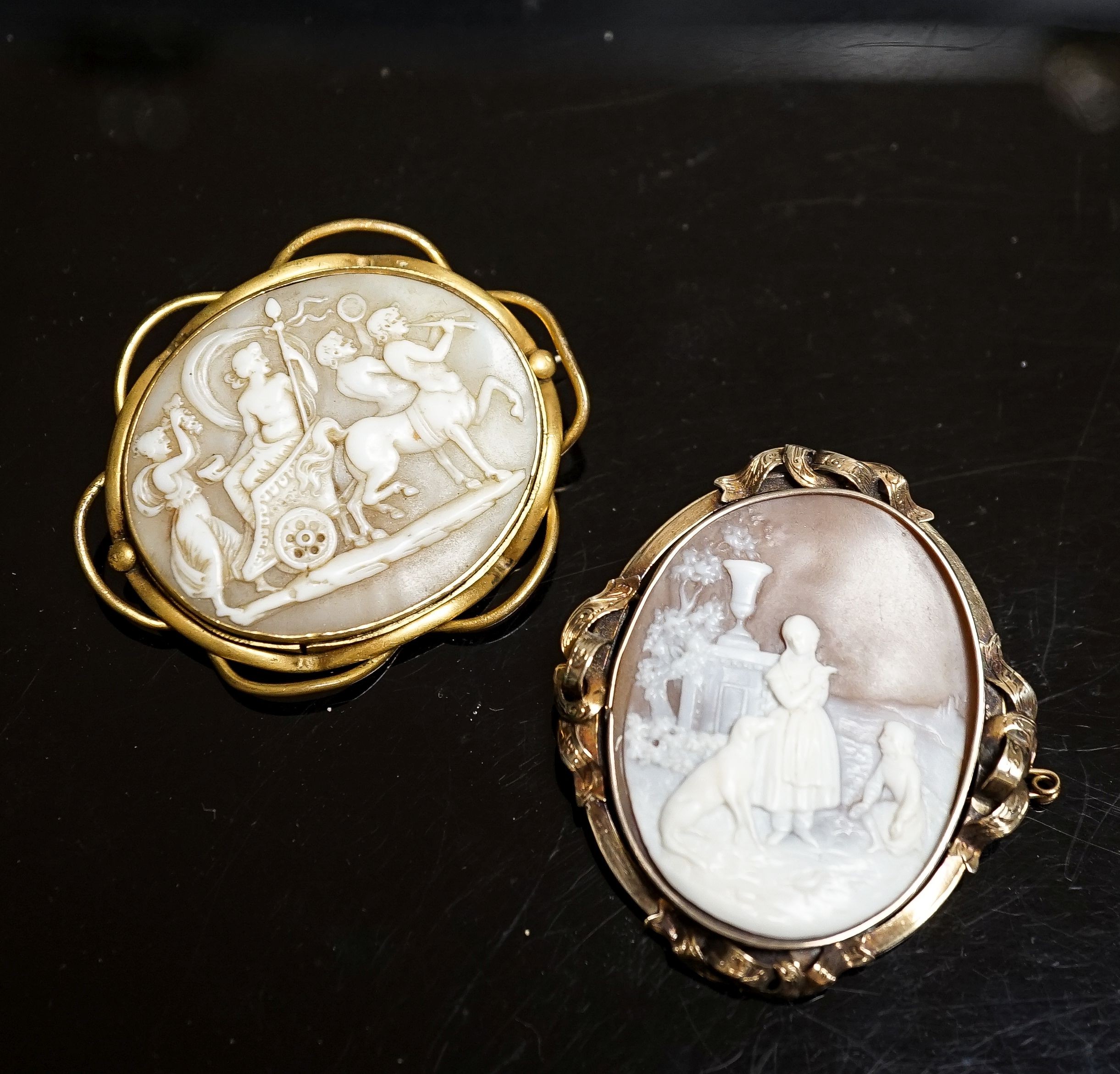 An Edwardian yellow metal mounted carved oval cameo shell and a gilt metal mounted cameo shell carved with chariot and mythical creatures, 52mm.